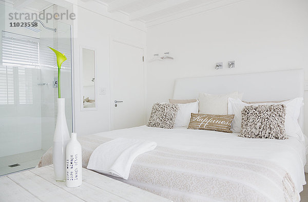 Weißes Schlafzimmer mit eigener Dusche in einem luxuriösen Hotelzimmer