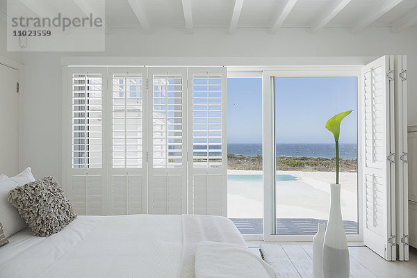 Schaufenster mit weißem Schlafzimmer  offen zum Schwimmbad und Meerblick