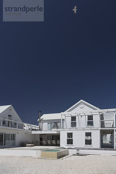 Weißes Haus und Swimmingpool unter sonnigem blauem Himmel