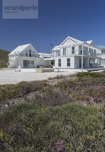 Weißes Strandhaus unter sonnigem blauem Himmel