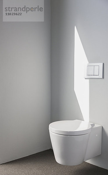 Sonnenlicht an der Wand über der modernen Toilette im Badezimmer