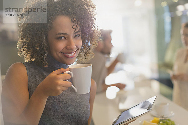 Porträt einer lächelnden Geschäftsfrau  die Kaffee trinkt und ein digitales Tablet benutzt