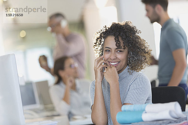 Lächelnde Geschäftsfrau  die im Büro mit einem Handy telefoniert