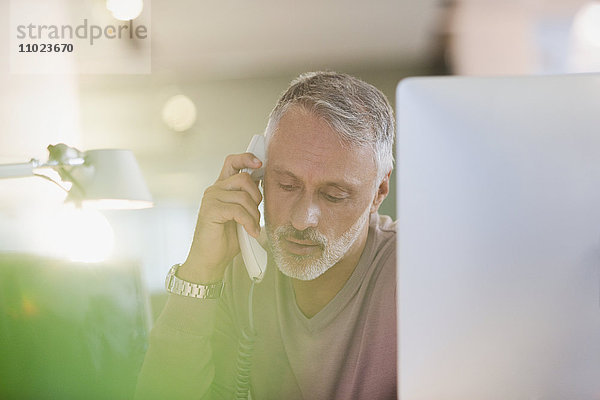 Geschäftsmann telefoniert am Computer im Büro