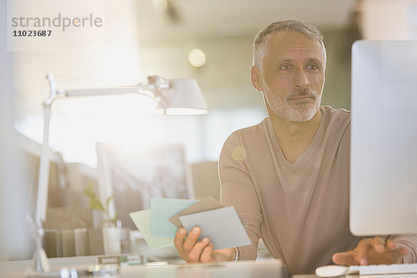 Designer mit Farbmustern bei der Arbeit am Computer im Büro