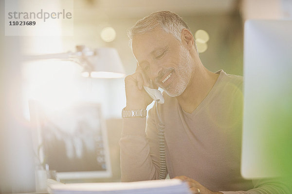 Geschäftsmann spricht am Telefon in einem sonnigen Büro