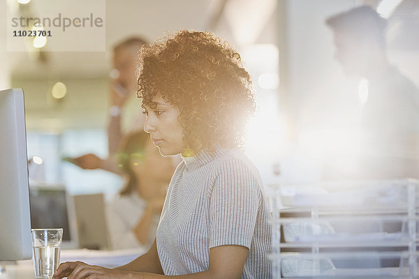 Konzentrierte Geschäftsfrau arbeitet am Computer in einem sonnigen Büro