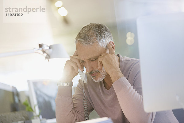 Seriöser Geschäftsmann am Telefon im Büro