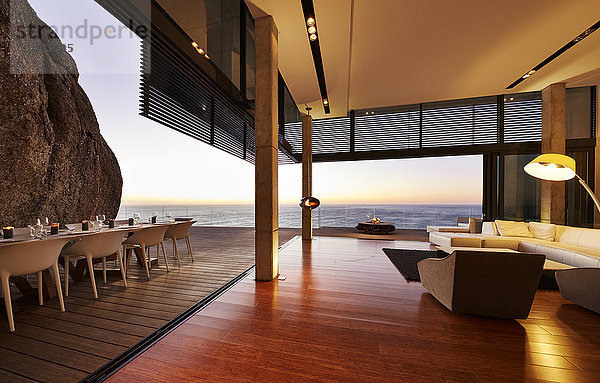 Modernes Luxus-Wohnzimmer mit Zugang zur Terrasse und Blick auf den Sonnenuntergang