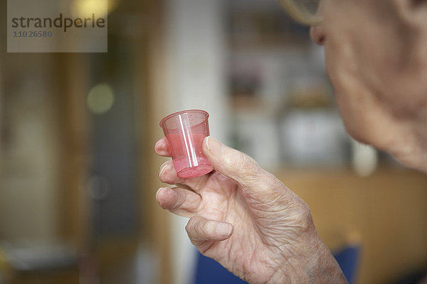 Senior nimmt Medikament in Seniorenheim