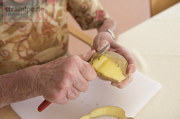 Seniorin schält Kartoffeln im Seniorenheim