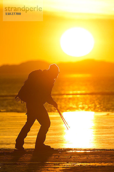 Mann beim Schlittschuhlaufen bei Sonnenuntergang