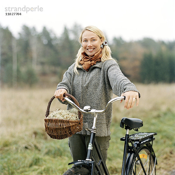 Eine blonde Frau mit Fahrrad an einem Herbsttag.