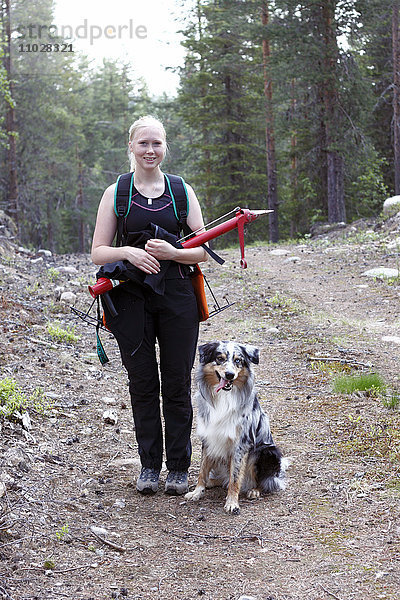 Lächelnde junge Frau mit Hund im Wald