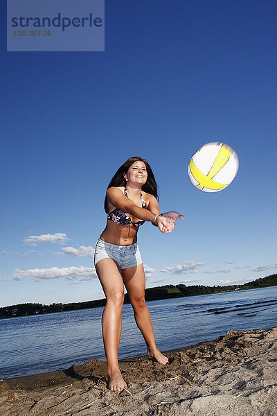 Frau spielt Volleyball am Strand