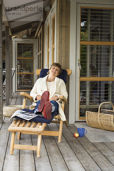 Eine Frau ruht sich in einem Liegestuhl auf einer Veranda aus.