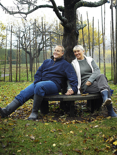 Ein Paar sitzt händchenhaltend auf einer Bank.