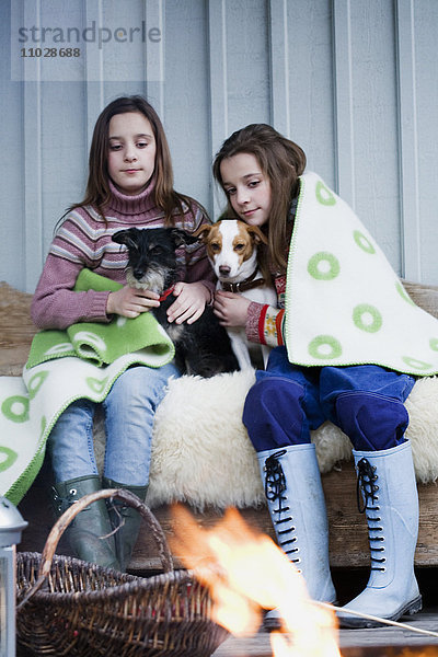 Mädchen mit Hunden sitzen am Lagerfeuer