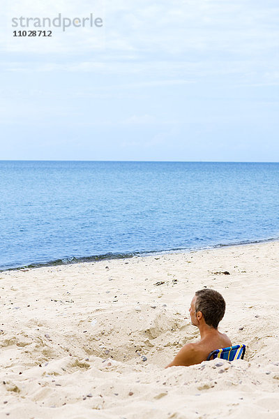 Mann entspannt sich im Sand am Strand