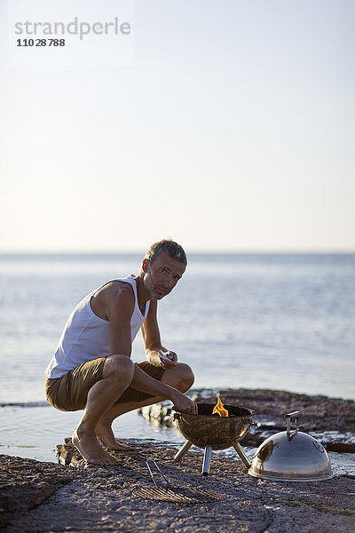 Mann bereitet Grillparty am Strand vor