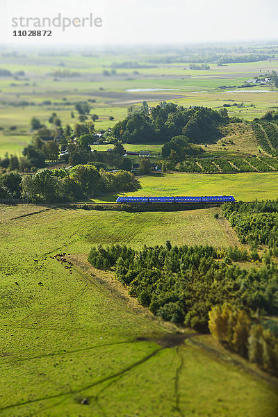 Luftaufnahme einer Landschaft mit vorbeifahrendem Zug