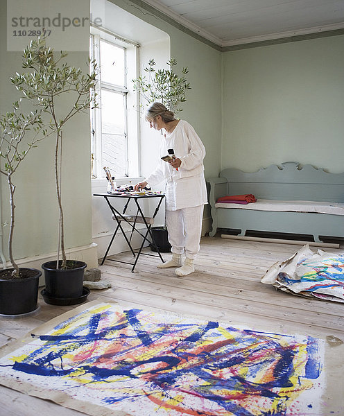 Eine Frau malt auf dem Boden.