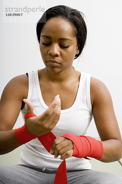 Eine Frau wickelt einen Verband um ihre Handgelenke.