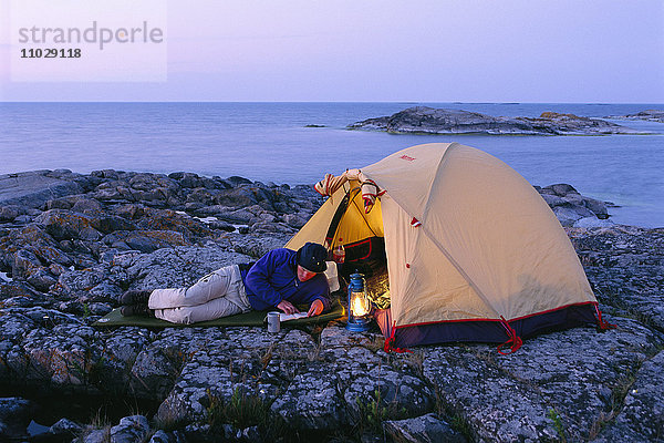 Ein Mann entspannt sich vor einem Zelt.