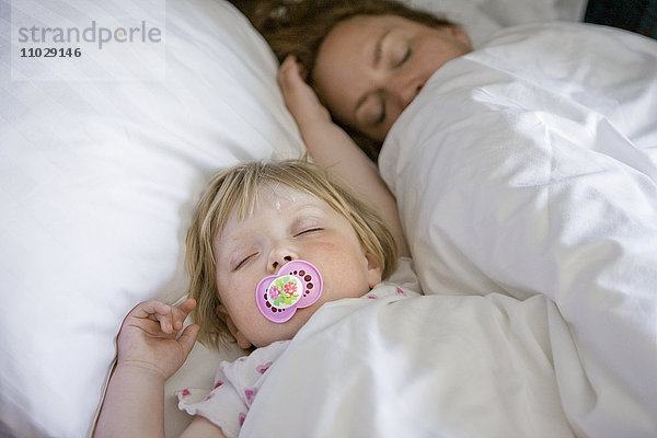 Mutter und Tochter schlafen auf dem Bett