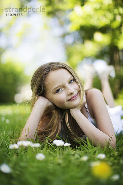Mädchen auf Rasen liegend  lächelnd  Porträt