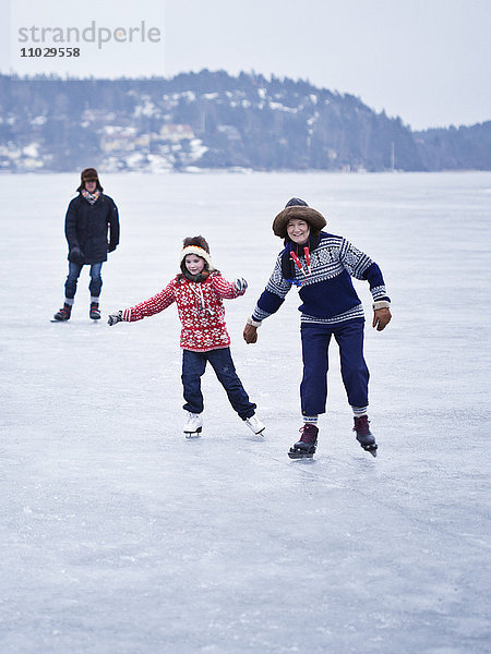 Familie beim Schlittschuhlaufen auf dem zugefrorenen See