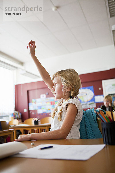 Schulmädchen hebt die Hand im Klassenzimmer