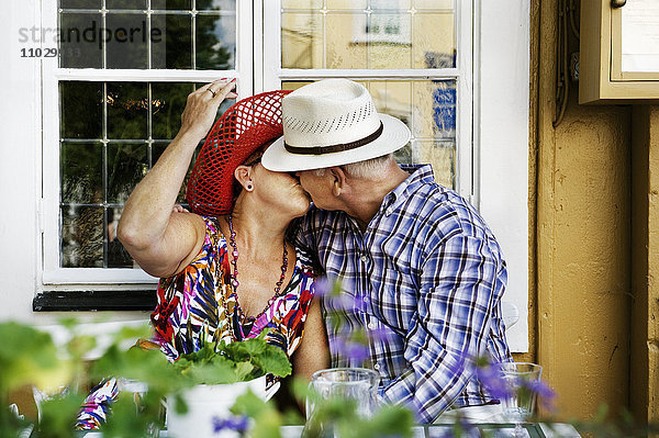 Reifes Paar  das sich vor einem Fenster küsst