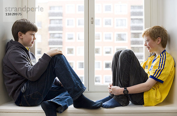 Zwei Jungen sitzen auf dem Fensterbrett