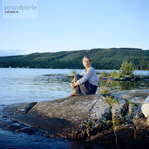 Frau sitzt am See