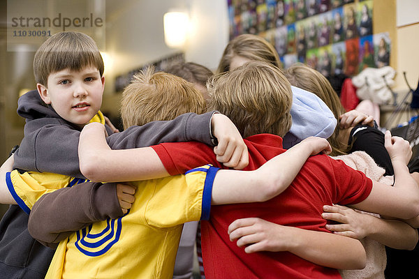 Kinder stehen im Kreis und umarmen sich