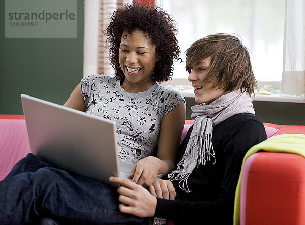 Teenager-Mädchen und Junge schauen auf Laptop