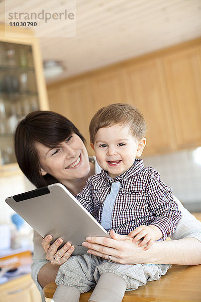 Mutter zeigt ihrem kleinen Sohn ein digitales Tablet