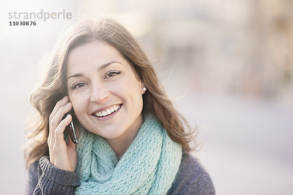 Porträt einer jungen Frau  die mit einem Handy telefoniert