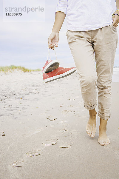 Frau am Strand trägt Schuhe  Nahaufnahme