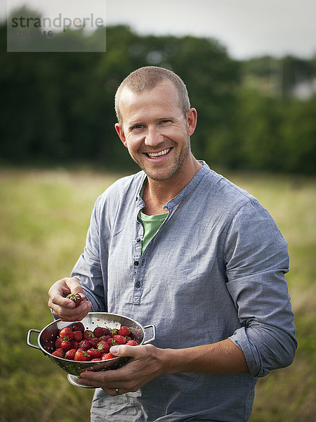Mann hält Schüssel voller Erdbeeren