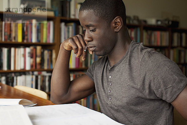 Porträt eines jungen Mannes  der in einer Bibliothek studiert