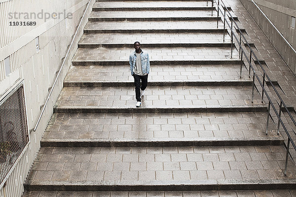 Erhöhte Ansicht eines jungen schwarzen Mannes  der eine Treppe hinuntergeht