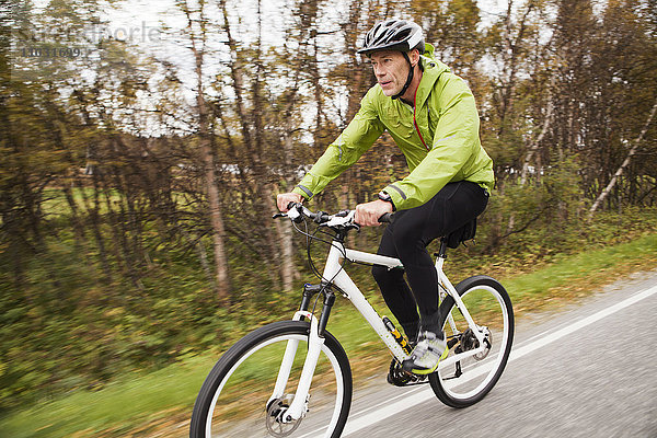 Älterer Mann mit Mountainbike auf der Landstraße