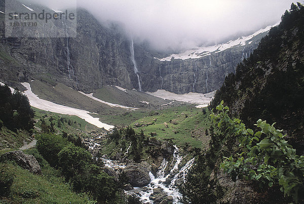 Blick auf einen Wasserfall in einem von Bergen umgebenen Tal