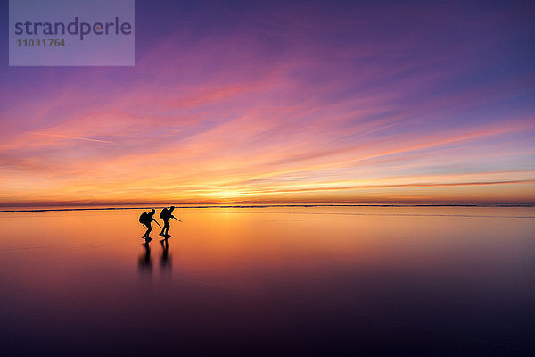 Menschen auf Schlittschuhen bei Sonnenuntergang  Vanern  Schweden