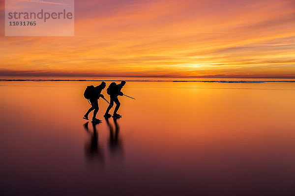 Menschen auf Schlittschuhen bei Sonnenuntergang  Vanern  Schweden