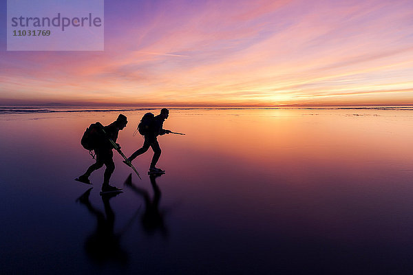 Menschen beim Schlittschuhlaufen bei Sonnenuntergang  Vanern  Schweden