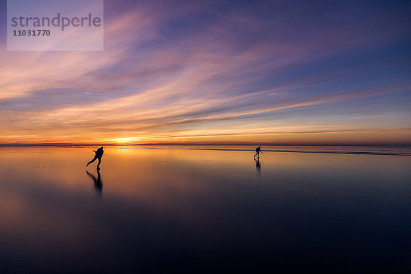 Menschen beim Schlittschuhlaufen bei Sonnenuntergang  Vanern  Schweden