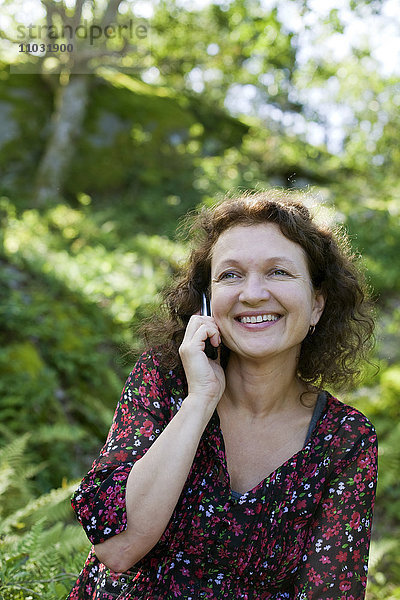 Lächelnde reife Frau  die über ein Mobiltelefon spricht